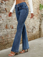 Person wearing blue flared jeans against a brick wall.