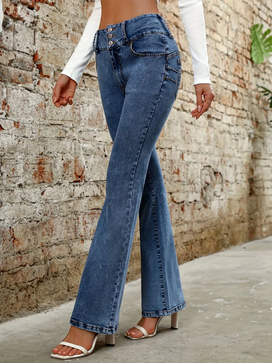 Person wearing blue flared jeans against a brick wall.
