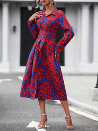 Woman wearing a red and blue patterned dress on a city street.