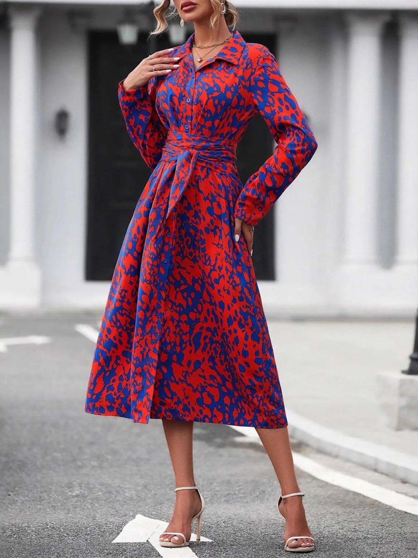 Woman wearing a red and blue patterned dress on a city street.