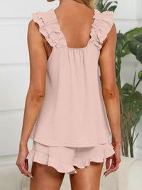 Woman wearing a pink ruffled top and shorts set with a white background