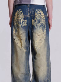 Blue jeans with gold angel wings design on a white background