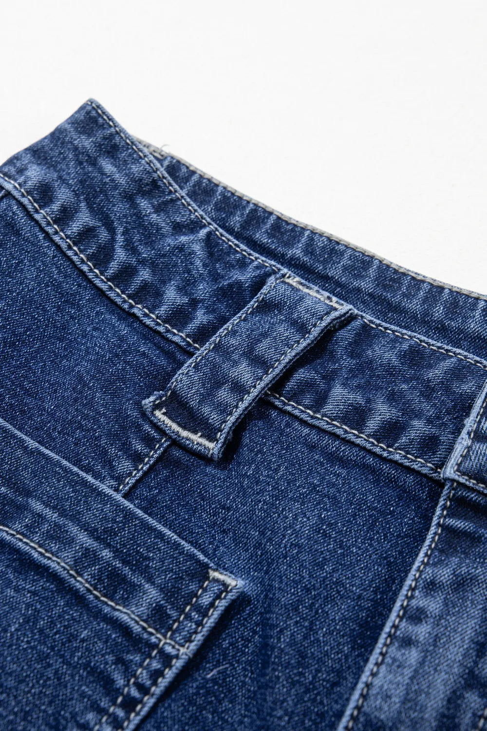 Close-up of blue denim fabric with stitching details on a white background