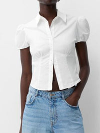 Person wearing a white short-sleeve blouse and blue jeans on a plain background