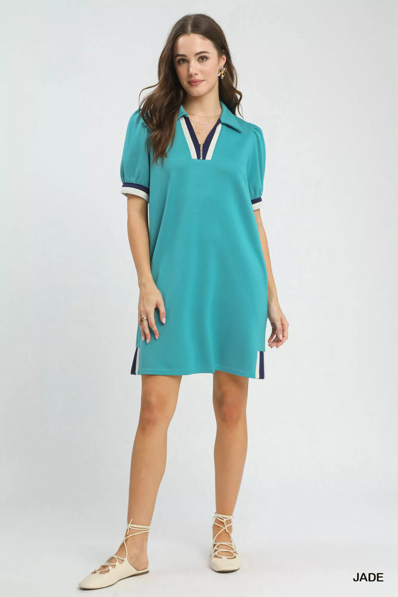 Woman wearing a teal dress with white accents on a light gray background