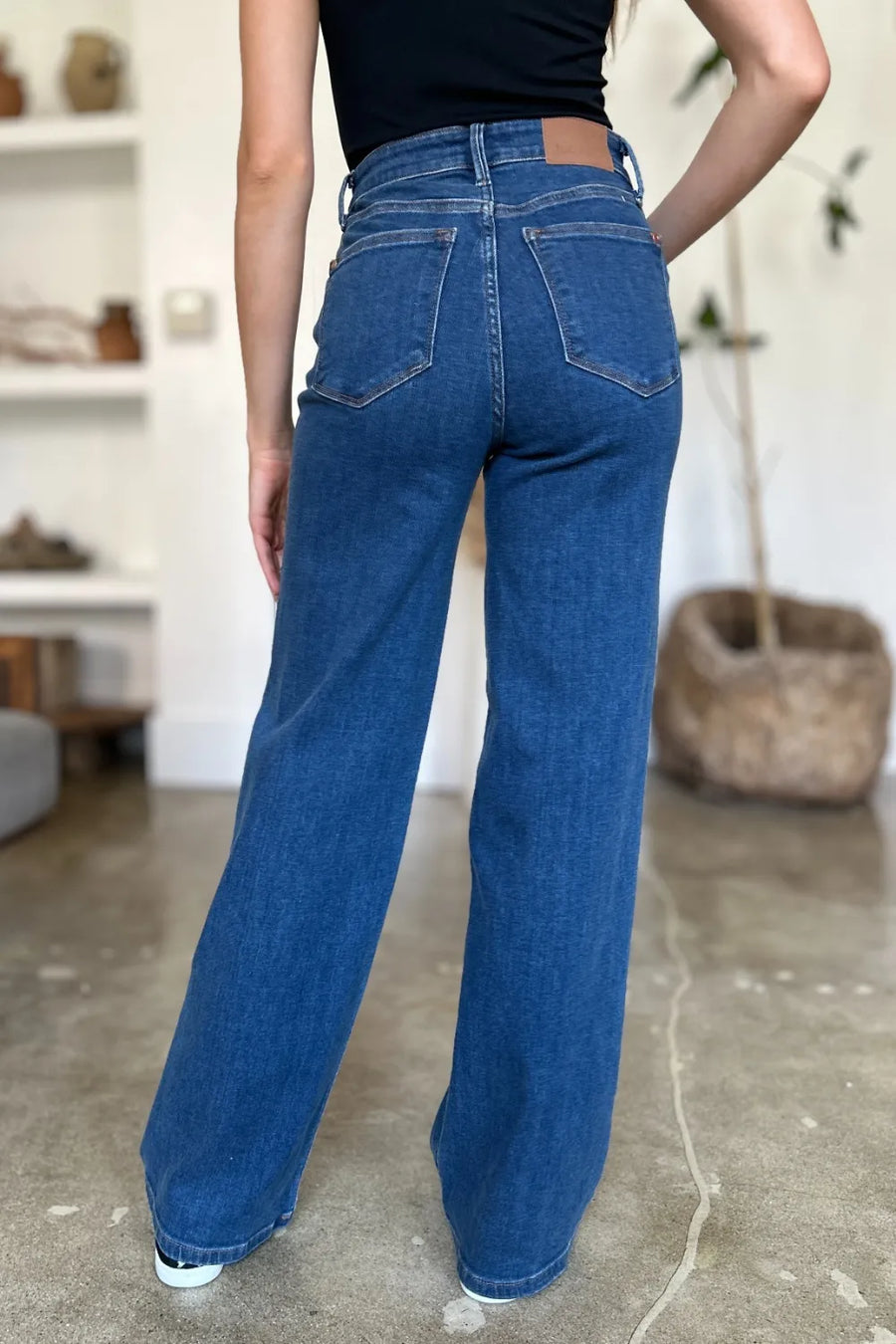 Person wearing blue jeans in a room with a neutral background