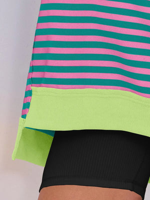 Close-up of a person wearing a colorful striped dress with green, pink, and black colors.