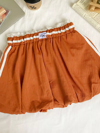 Orange shorts with white trim on a white surface