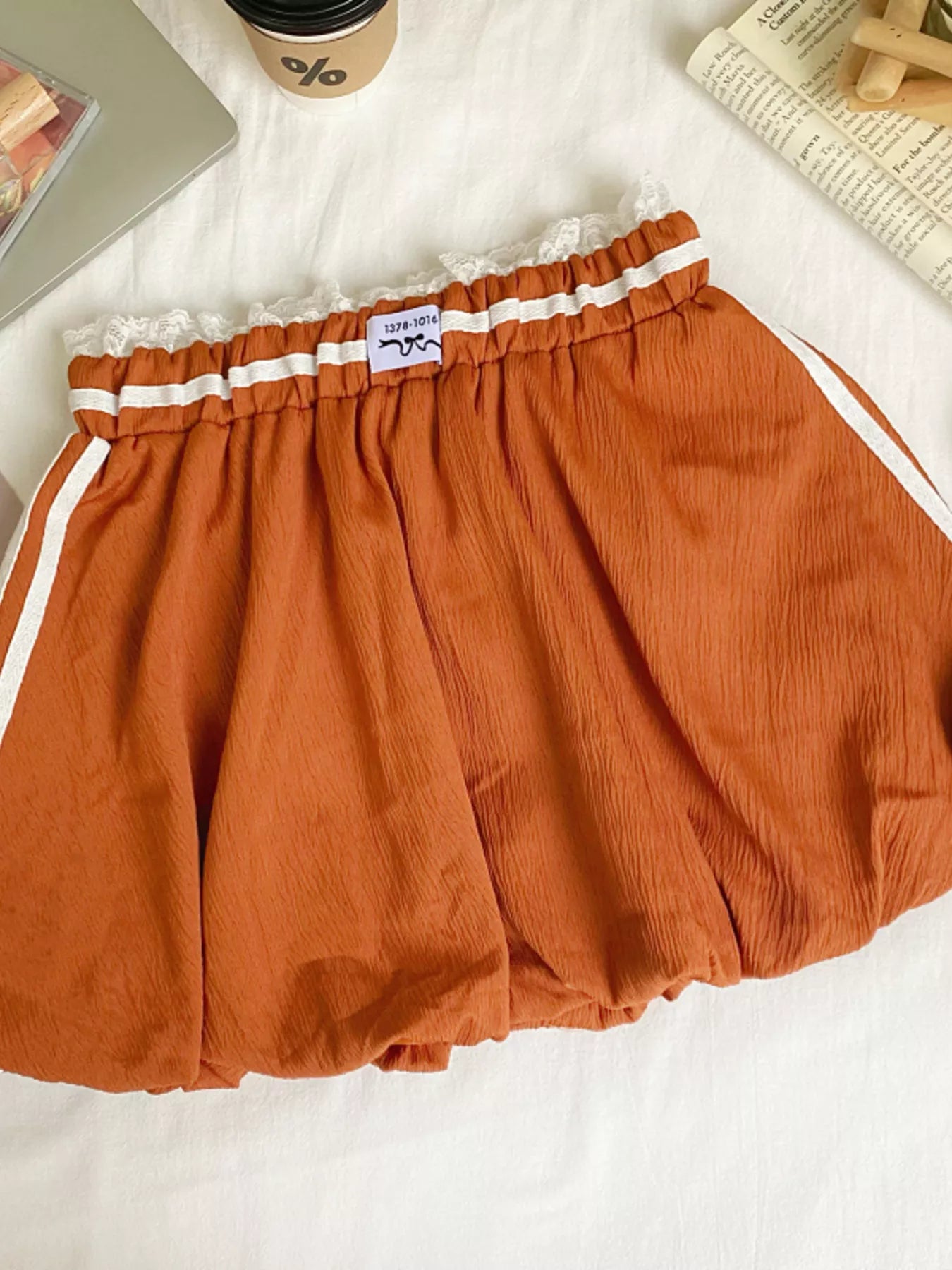 Orange shorts with white trim on a white surface