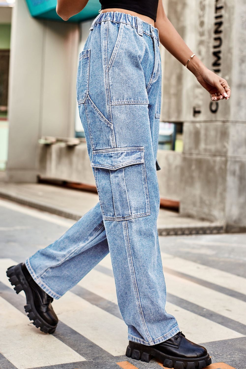 Person wearing blue jeans and black shoes walking on a street.