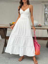 Woman in a white dress holding a pink bag on a patio