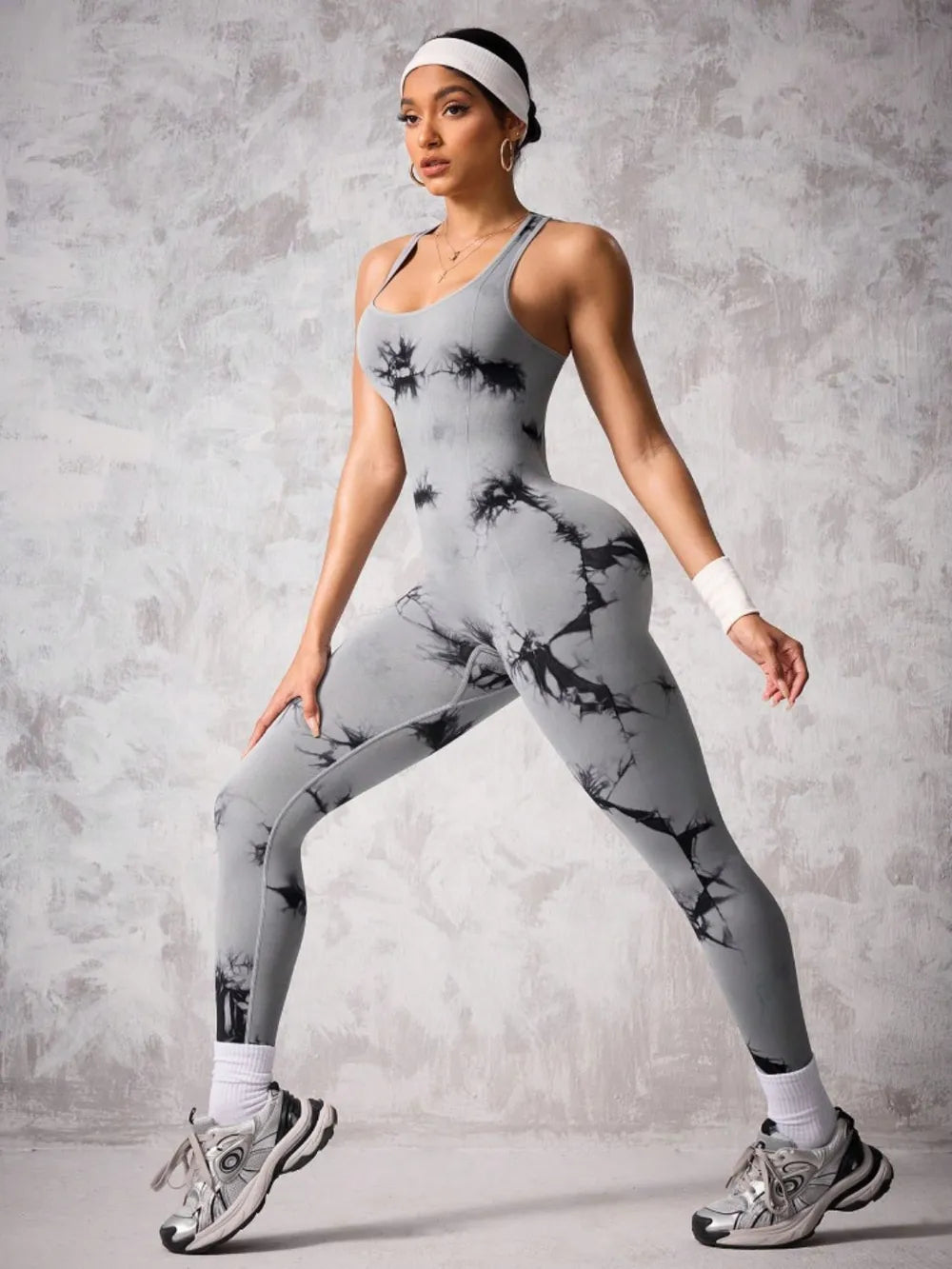 Woman wearing a gray and black tie-dye athletic outfit on a gray background