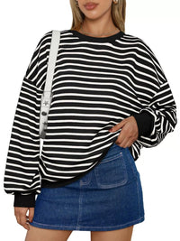 Person wearing a black and white striped sweater with a denim skirt on a white background
