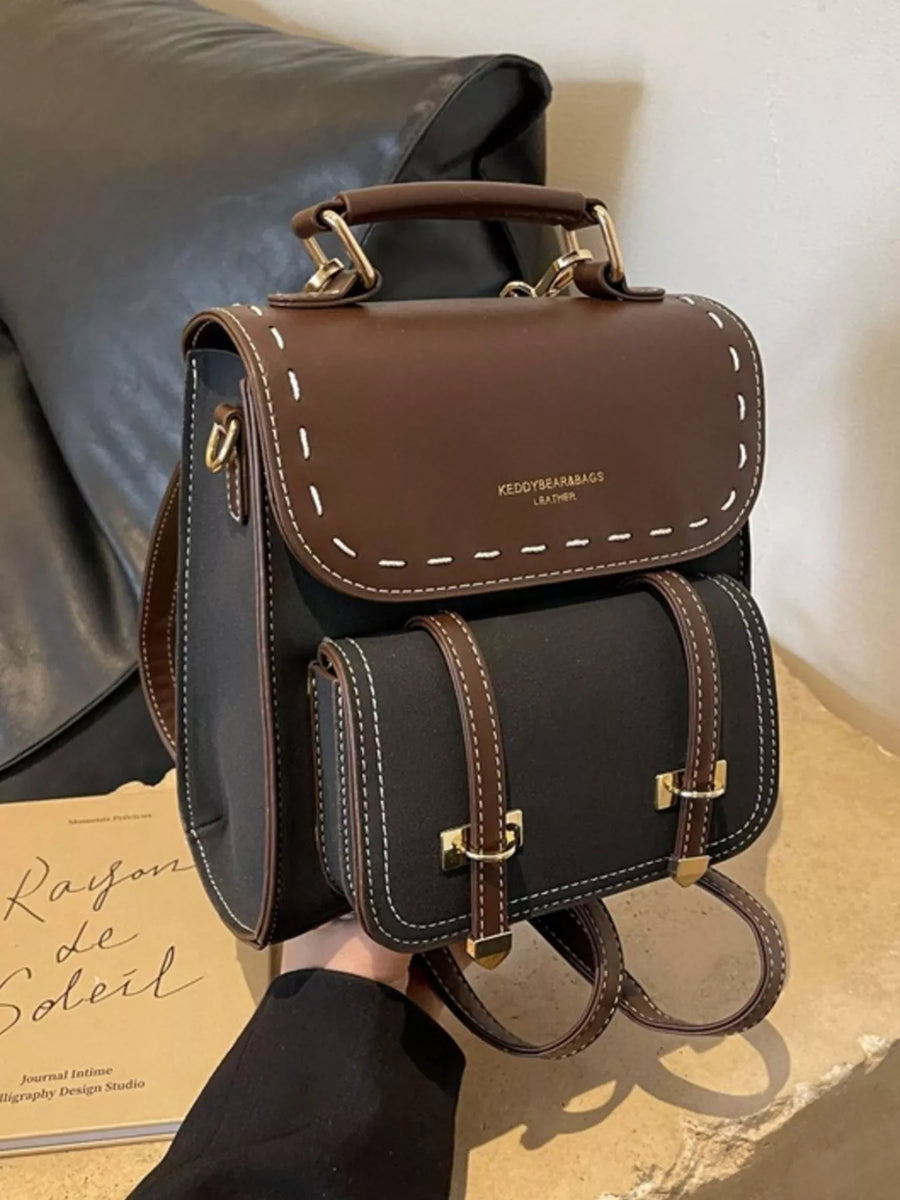 Brown leather backpack with gold accents on a neutral background
