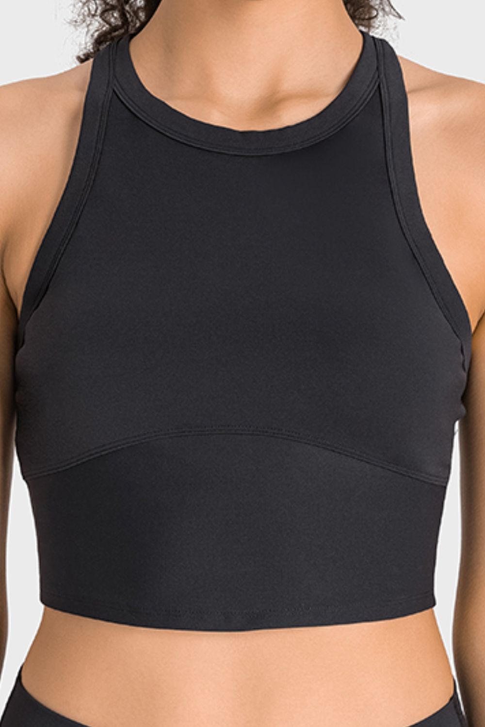 Black sports bra worn by a person on a light gray background