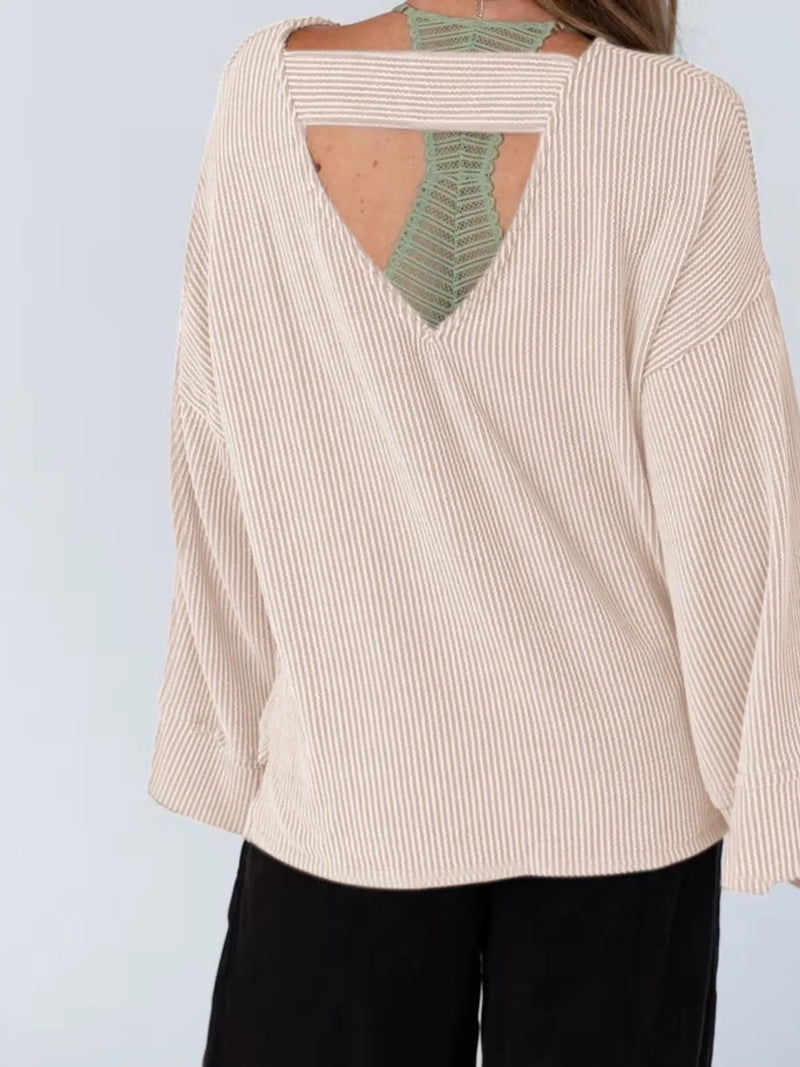 Beige ribbed sweater with open back worn by a person on a light gray background