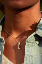 Person wearing a gold necklace with a pendant, close-up of neck and denim jacket.