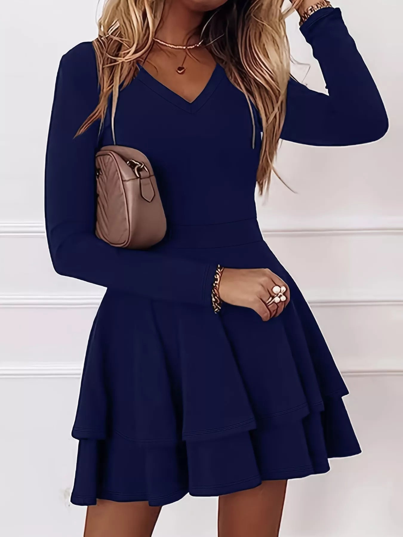 Woman wearing a navy blue dress with long sleeves and a white background
