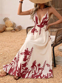 Woman wearing a white dress with red floral patterns sitting on a wicker chair.