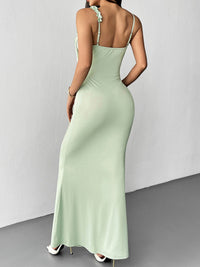 Woman wearing a light green dress with thin straps against a plain background