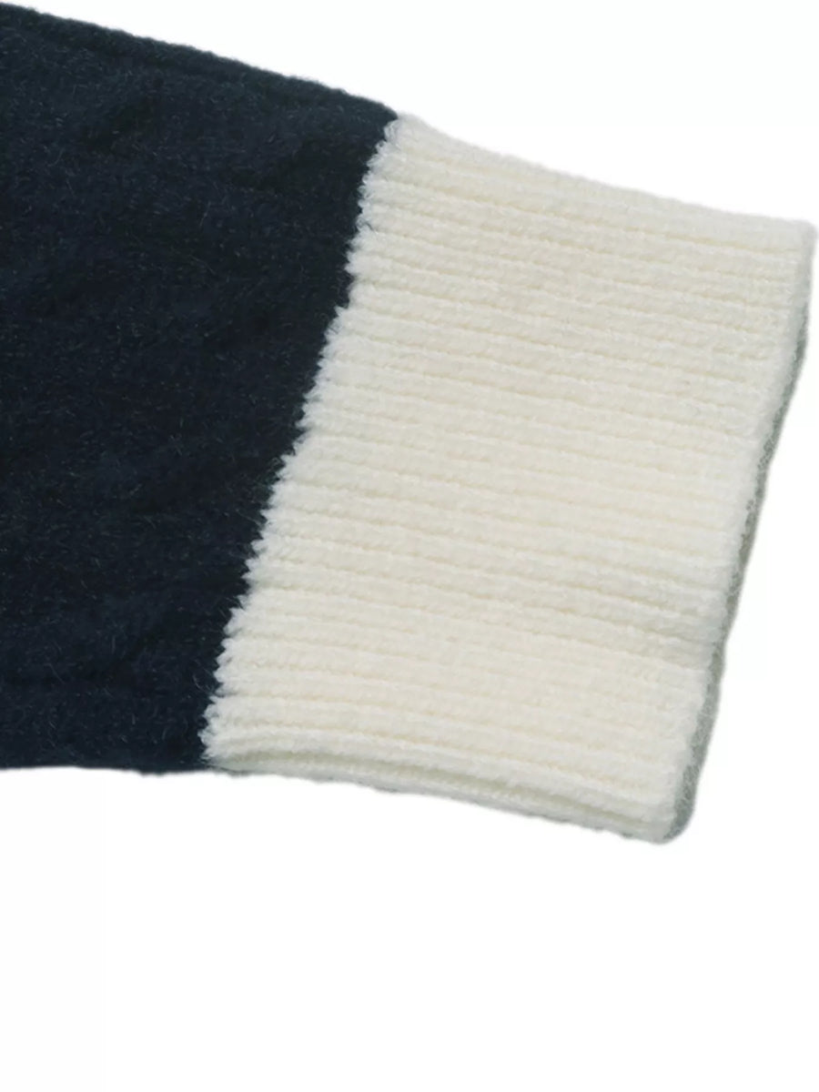 Close-up of a ribbed knit sleeve or cuff with a dark navy blue section and an off-white ribbed section, shown on a plain white background.