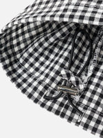 Close-up of a black and white gingham checkered fabric product with a black drawstring and silver metal toggle, photographed on a light gray background.