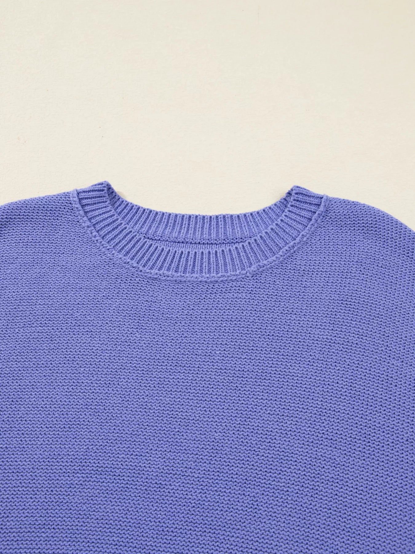 Close-up of a blue sweater with a beige background
