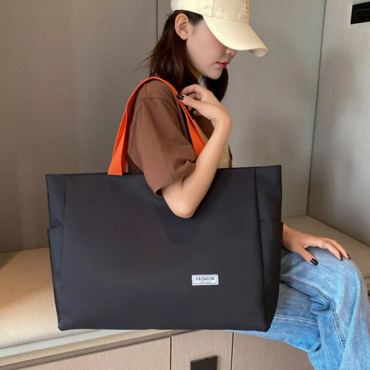 Woman holding a black tote bag with an orange interior, sitting on a bench.