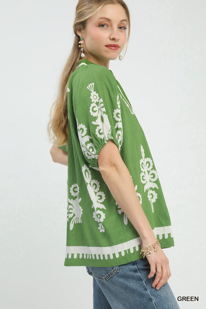 Woman wearing a green top with white patterns on a white background