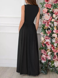 Woman wearing a black sleeveless dress standing next to a floral arrangement.