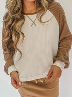 Person wearing a beige and brown sweater with a plain background