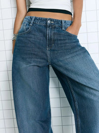 Person wearing blue jeans against a white tiled wall