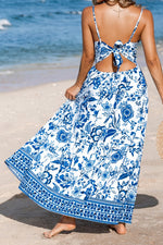 Woman wearing a blue and white floral dress on a beach.