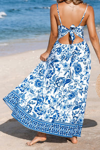 Woman wearing a blue and white floral dress on a beach.