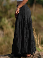 Person wearing a long black skirt standing outdoors with a blurred natural background