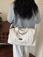 Person holding a beige bag with a visible brand logo indoors.