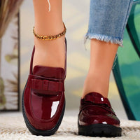 Red loafers worn with denim jeans on a blurred outdoor background