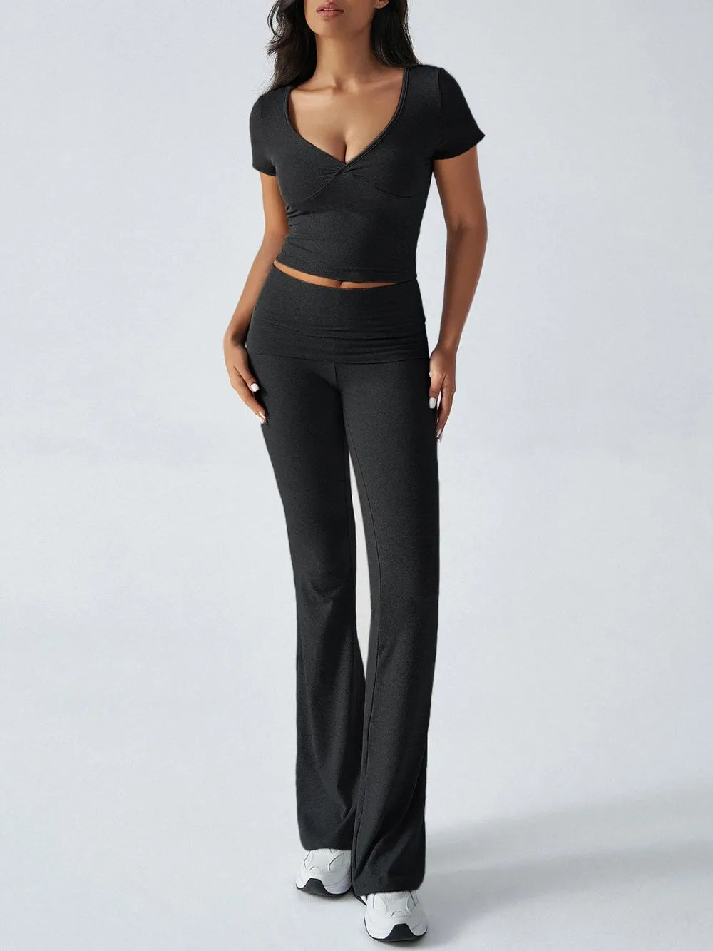 Woman wearing a black outfit with a top and wide-leg pants on a white background