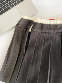 Gray pleated skirt with a laptop and notebook on a white surface