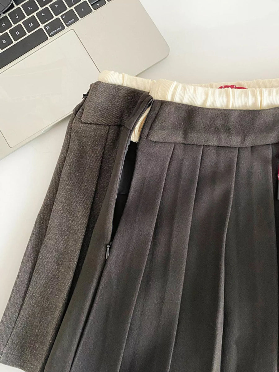 Gray pleated skirt with a laptop and notebook on a white surface