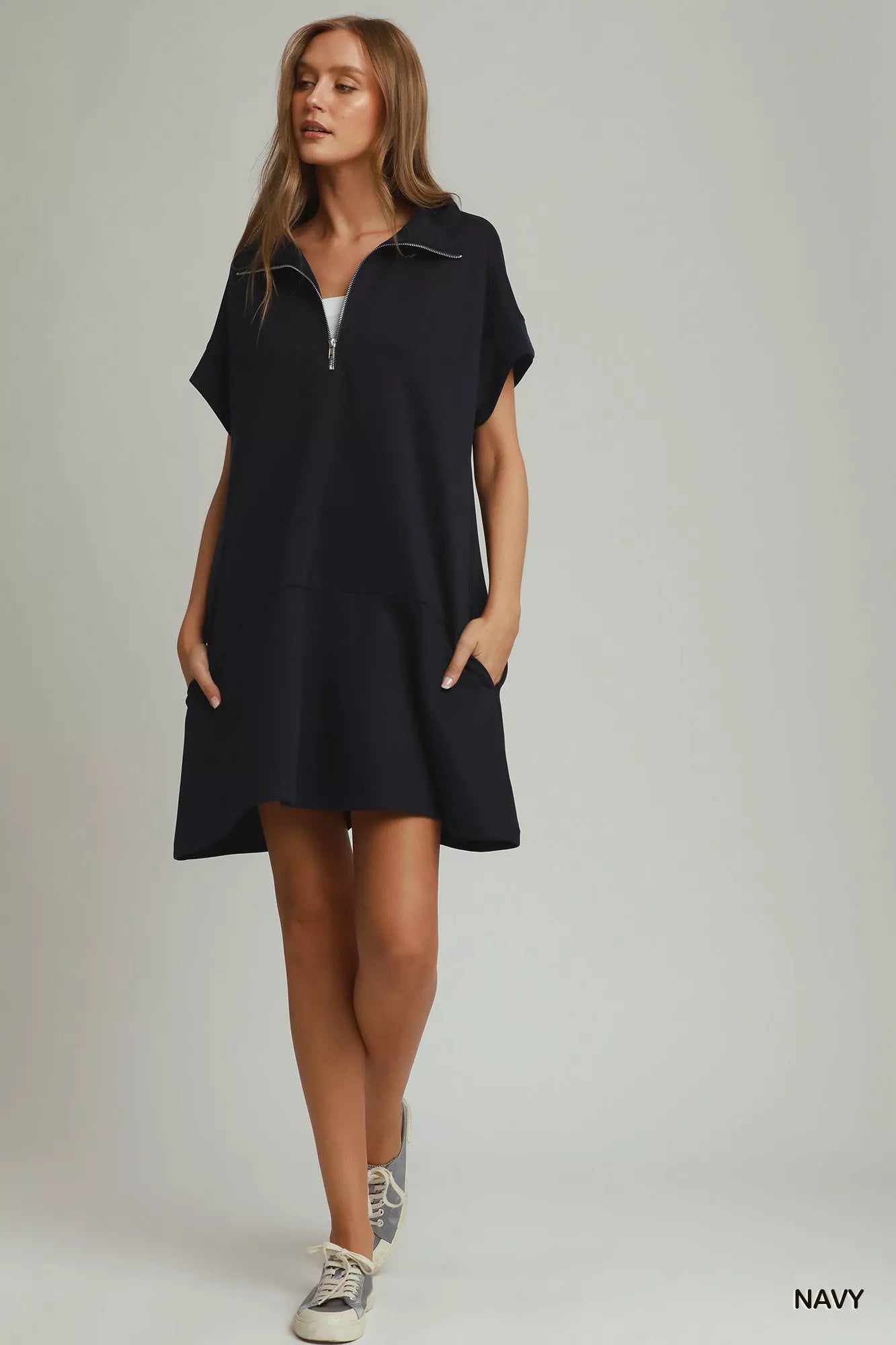 Woman wearing a navy dress on a plain background