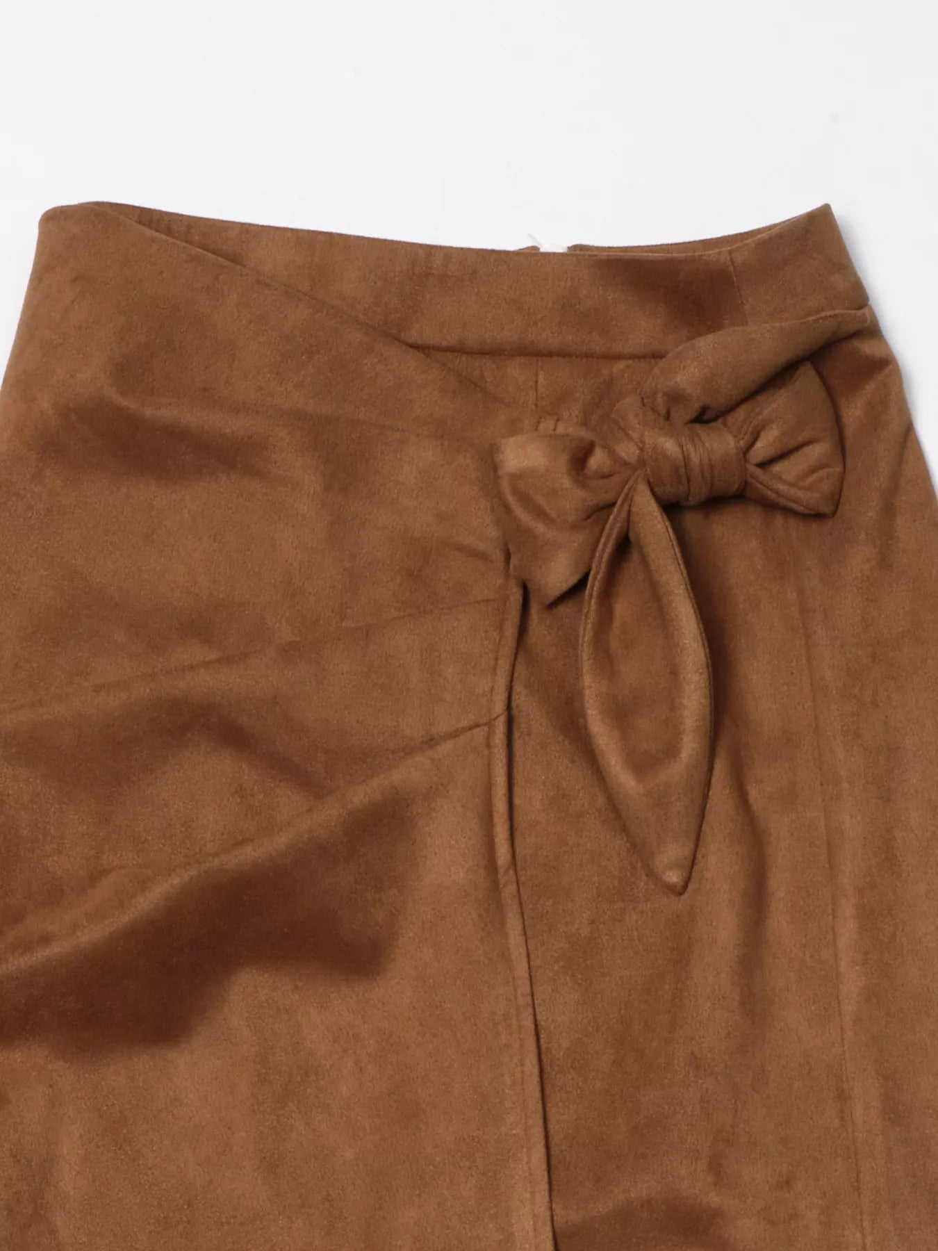 Brown suede skirt with a bow detail on a white background