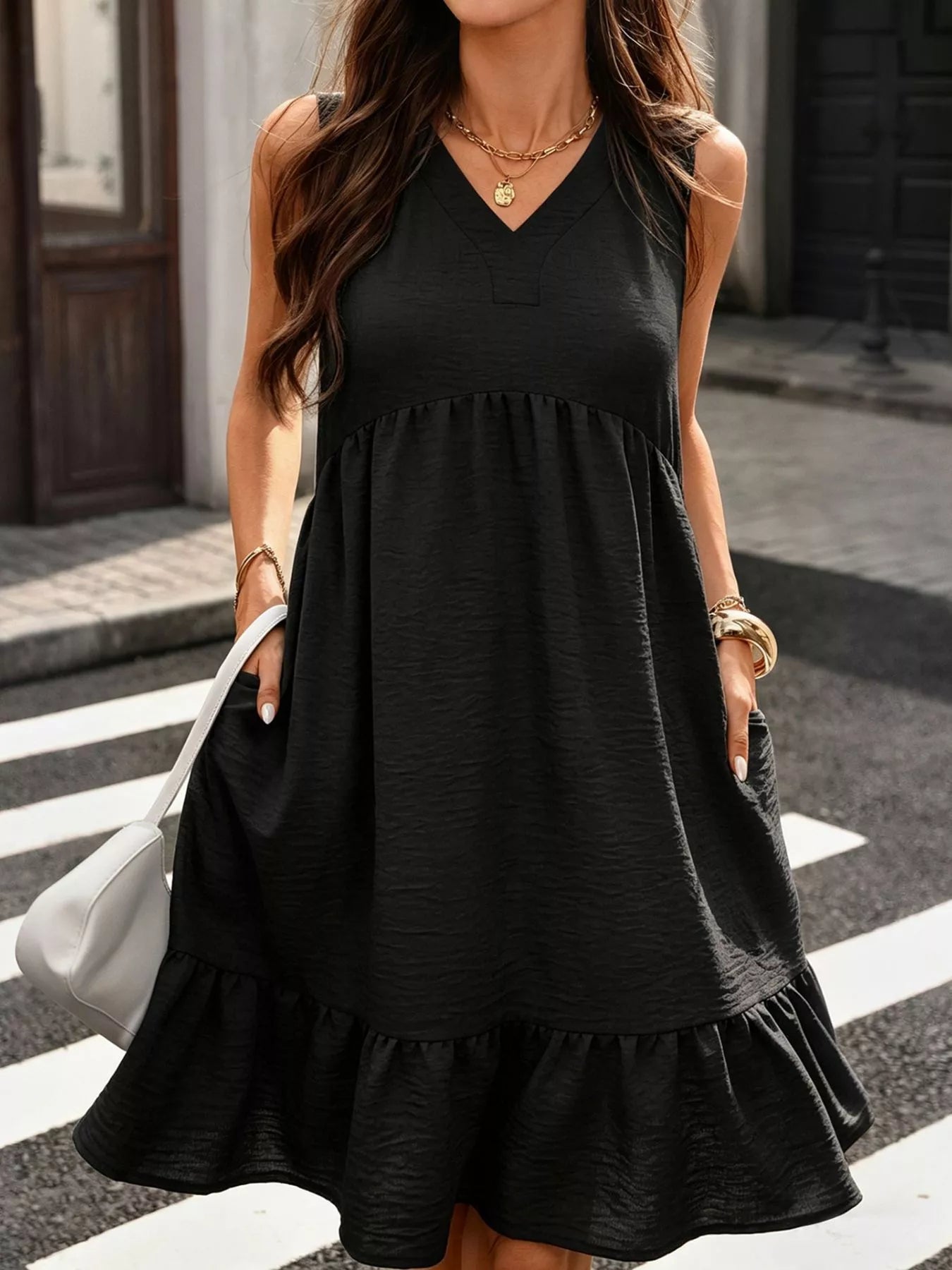 Woman wearing a black sleeveless dress on a city street.