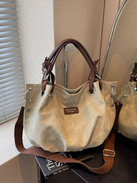Beige handbag with brown leather straps on a surface