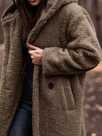 Person wearing a brown teddy coat with a blurred background