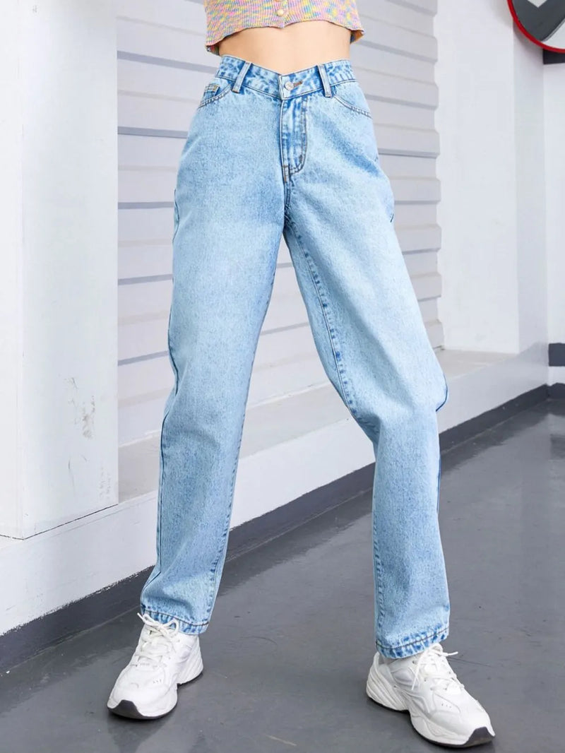 Person wearing light blue jeans and white sneakers in a minimal indoor setting