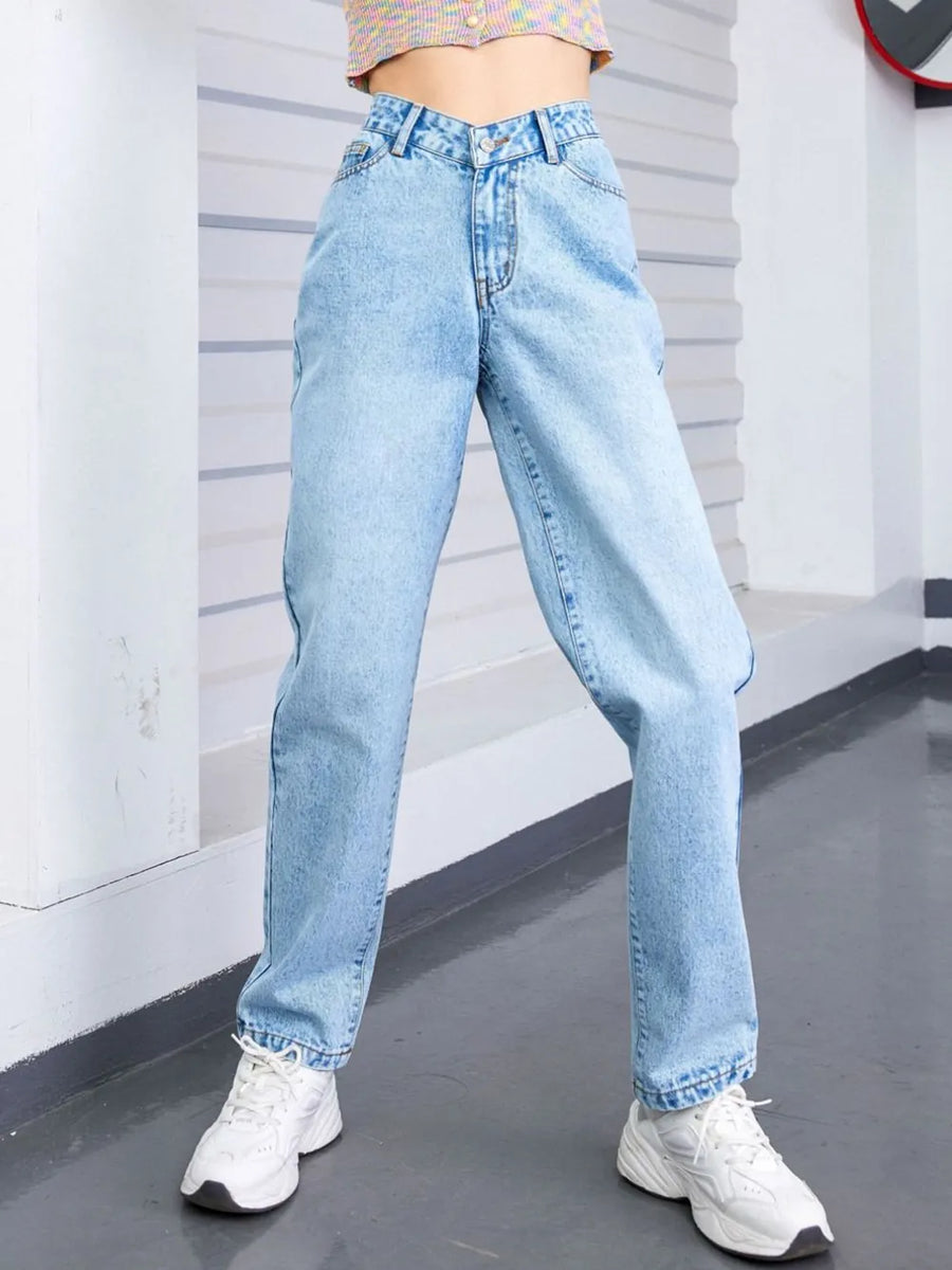 Person wearing light blue jeans and white sneakers in a minimal indoor setting