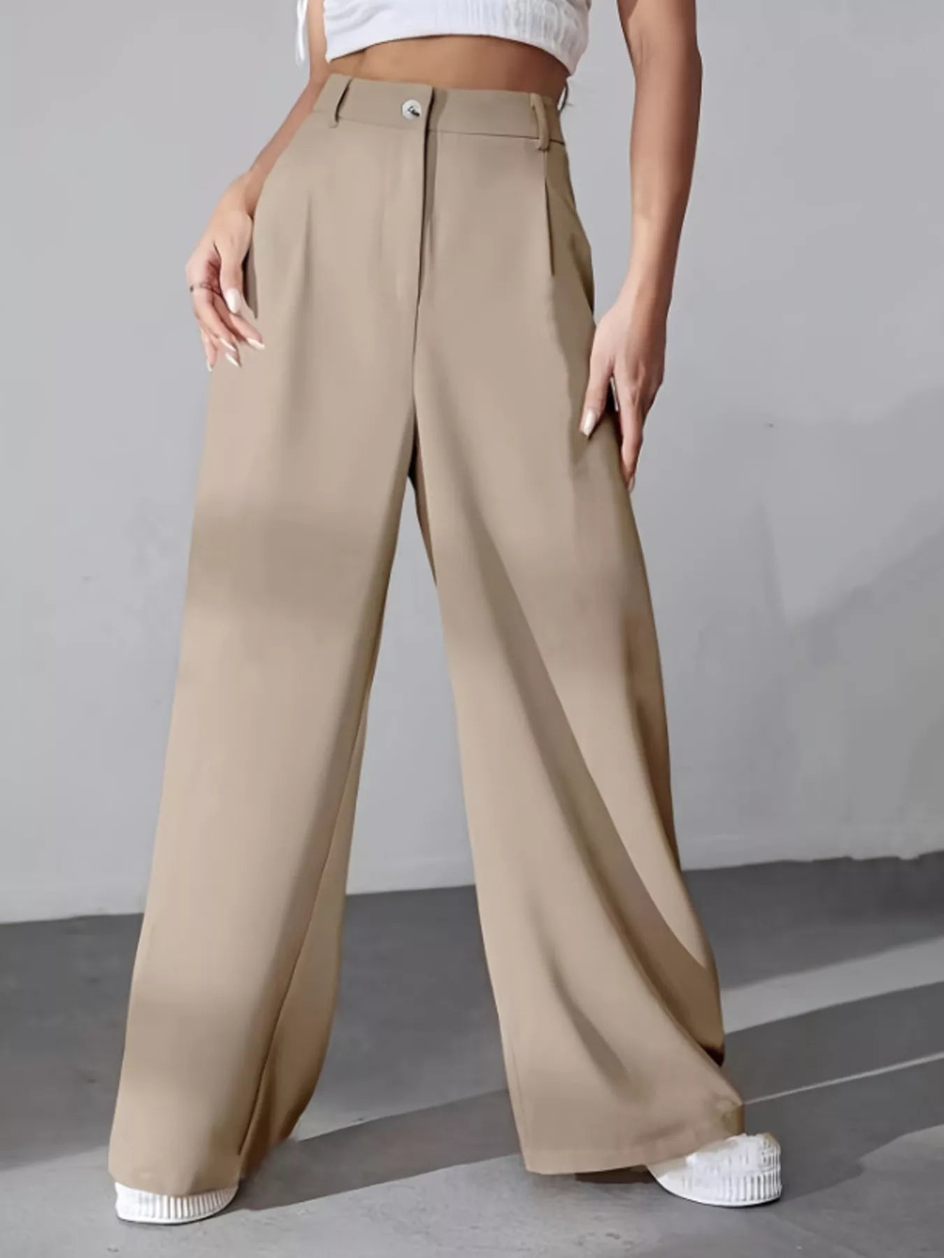 Beige wide-leg pants worn by a person on a gray background