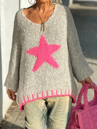 Person wearing a gray sweater with a pink star design, holding a pink bag.