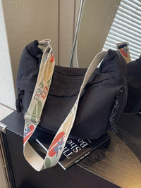 Black bag with a colorful strap on top of a book